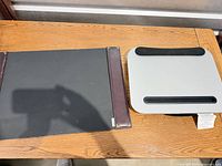 Grey plastic laptop stand with black foam rests beside black board