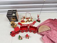 All items grouped: wooden train pieces, boxed music box, gourd snowman, God Jul plaque, two gnomes, small house with elf, nativity relief wrapped