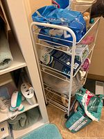 Full view of white wire cart next to shelving unit, contents inside