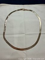 Full view of gold-tone herringbone necklace laid flat