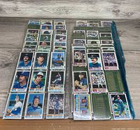 Two columns of sleeved 1982 Topps baseball cards laid out on wood surface