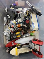 Top view of tub showing mixed Lego bricks, vehicle sections, boat hull, police panels