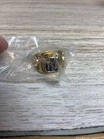 Ring in sealed plastic bag showing face with blue NY logo