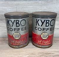 Front view of two Kybo Coffee tins showing graphics and wear