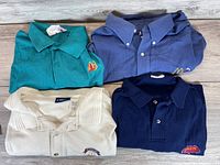Four folded McDonald's shirts in teal, blue, cream and navy showing embroidery