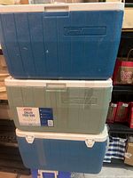 Stacked view of three Coleman coolers showing colors and lids