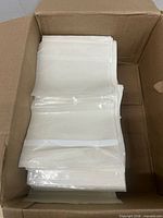 Box filled with stacked clear self-adhesive shipping label sleeves