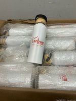 Open box showing several white metal bottles with bamboo lids wrapped in bubble wrap; one bottle unwrapped displaying Centrum logo