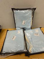 Three sealed baby blue bedding sets on table