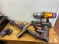 Full lot showing vacuum body, wand, two large heads, mini head, charger, dock