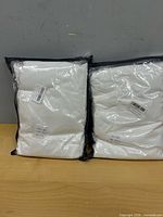 Two factory-sealed white bedding sets in clear zip bags