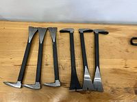 All six nail puller pry bars laid out on tabletop showing both ends
