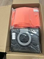 View into box showing orange item and black tablet case