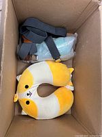 Top view showing neck pillow and cross-body pouch in box