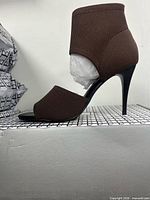 Side profile of right heel showing brown stretch fabric upper and stiletto heel