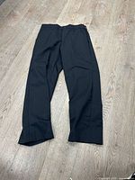 Full view of black work pants laid flat on floor