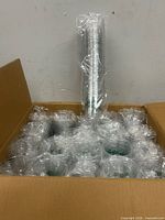 Open carton showing numerous wrapped sleeves of clear plastic cups
