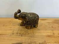 side view of brass elephant showing trunk and ornate body patterns