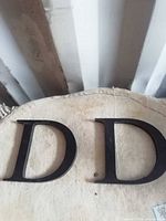 Two black wooden letter Ds on fabric surface