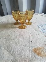 Front view of three amber pressed glass footed goblets