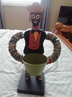 Front view of bottle cap folk art figure holding bowl