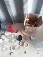 overview of table with assorted candles and holders, box containing more candles