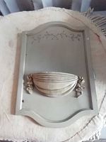 Front view of painted plaque showing planter bowl and vine motif