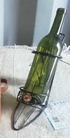 side view of metal stiletto wine bottle holder with green bottle inside