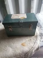 Front view of green metal toolbox showing hinged lid and dual latches