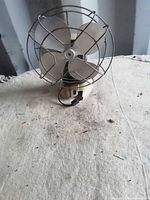 Front view of beige plastic fan with metal cage and four blades