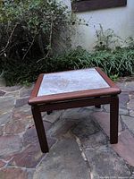 full view of square teak end table outdoors