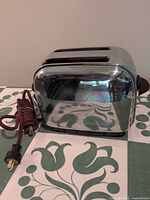 Full view of chrome two-slot toaster with cloth power cord visible