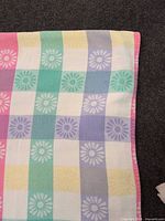 Edge of tablecloth showing pastel check and daisy weave