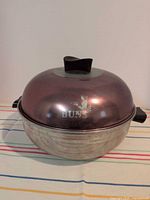 Warmer assembled showing copper-tone lid and black handles