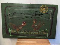 Full view of painting on green board showing entire composition with two birds and yellow sun