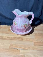 Front view of marbled pink ceramic pitcher on basin showing floral decals
