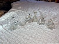 Front view of all six clear glass cruets and decanters lined up