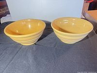 Two yellow stoneware mixing bowls side by side, interior view