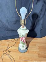 Front view showing floral ceramic body, base, harp and bulb