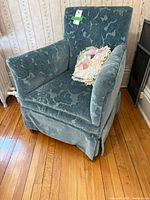 Front view of blue floral upholstered armchair with skirt and pillow