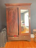 Front view of armoire showing mirrored door, drawers, finish wear