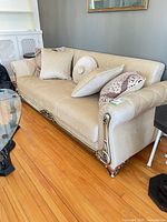 Full view of beige crushed velvet sofa with throw cushions and carved accents