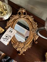 Ornate oval mirror with gold frame on shelf