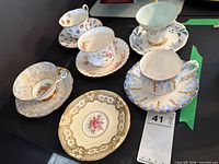 Overview showing five Royal Albert cup-saucer sets and Aynsley saucer