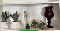 Shelf view showing candle holder, porcelain lady, beaver figurine, two turtle planters, two cottage figurines, small white animal