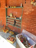 Overall lot showing storage bin with florals, candles in basket, metal candle stand and pumpkins
