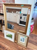 Front view showing mirror and two smaller framed prints leaning against it