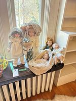 Group shot of all six porcelain dolls on windowsill