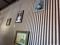 Wide view of all framed prints on striped wall showing both listed royal portraits