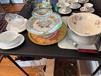 Group view showing Noritake bowl, Limoges plate beneath glass stand, crystal bowl, serving tray and cake stand